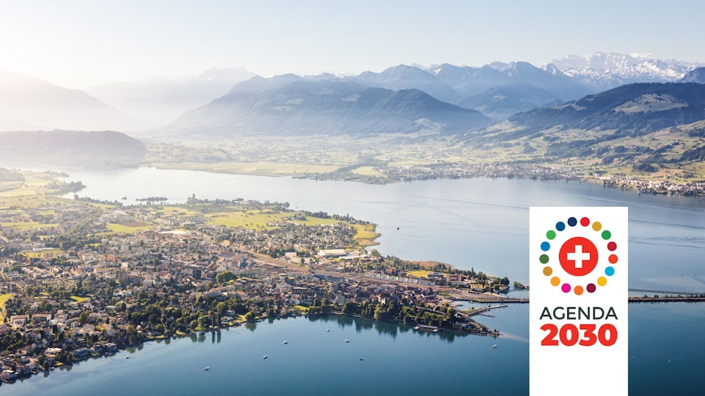 Typical Swiss landscape with a meadow, village, lake and mountains, with a logo featuring the Swiss cross surrounded by dots and the words “Agenda 2030”.