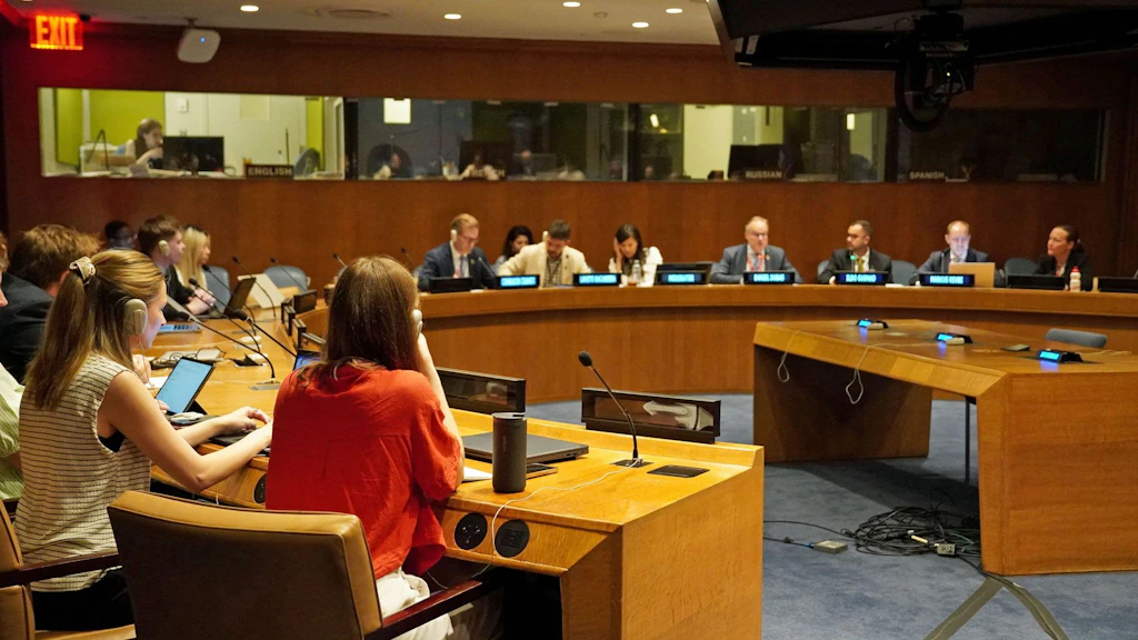 Salle de conférence où les participants sont assis autour de tables disposées en demi-cercle.